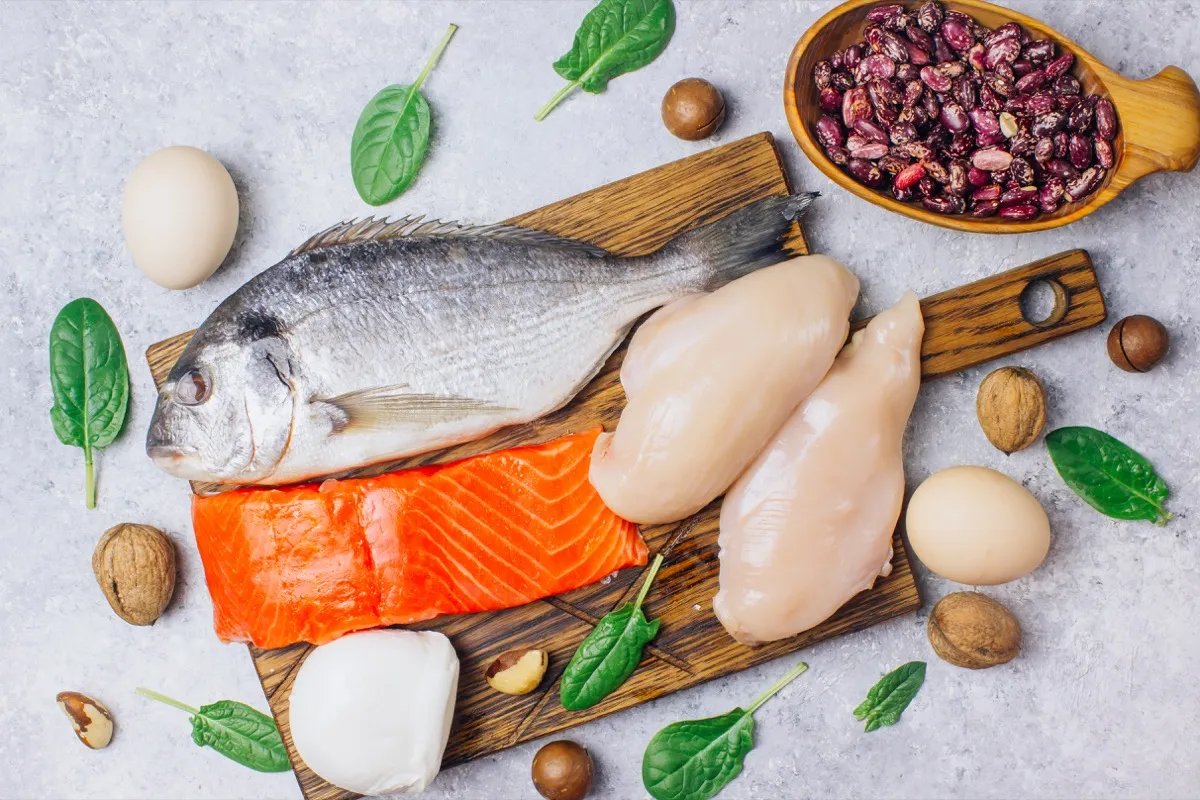 A variety of healthy protein sources and body-building foods.  Salmon, chicken breast, eggs, mozzarella cheese, beans, nuts, spinach, flax and chia seeds.  Top view.  bright background